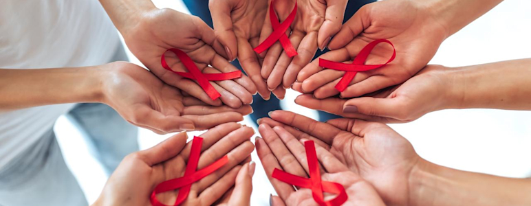 Zum Welt AIDS Tag: Solidarität mit den Betroffenen. Viele Hände halten rote Schleifen.