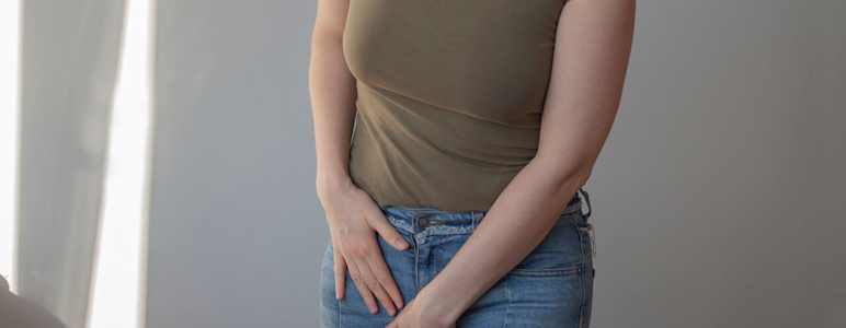 Frau hält eine Hand in ihren Intimbereich.