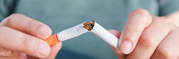 Im Fokus stehen zwei Hände, welche eine Zigarette in der Mitte durchbrechen.