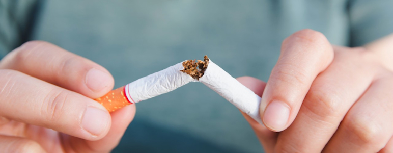 Im Fokus stehen zwei Hände, welche eine Zigarette in der Mitte durchbrechen.