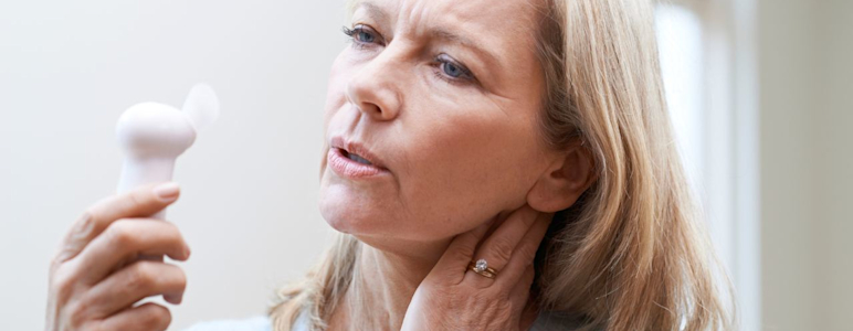 Hormonersatztherapie (HET). Frau mit Hitzewallungen hält Ventilator.