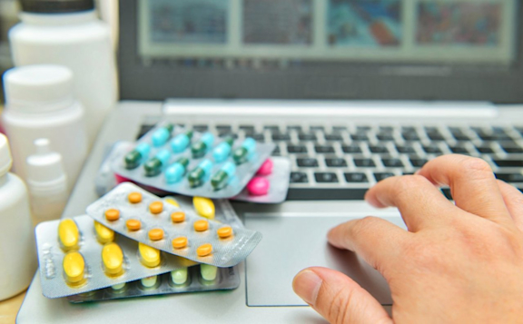 Einkauf Online-Apotheke mit Tabletten auf Laptop.
