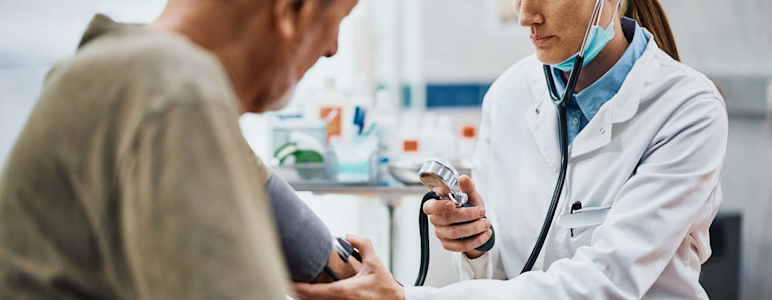 Junge Ärztin misst bei ihrem Patienten den Blutdruck.