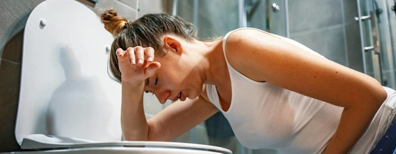 Frau erbricht sich auf der Toilette.