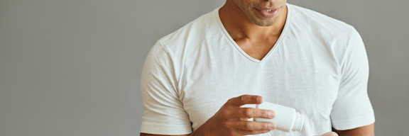 Ein junger mann mit Glatze schüttet sich Tabletten in die Hand.