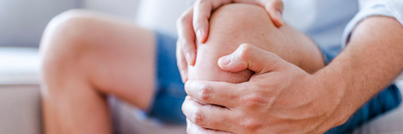 Ein Mann hält sich vor Schmerzen das Knie.