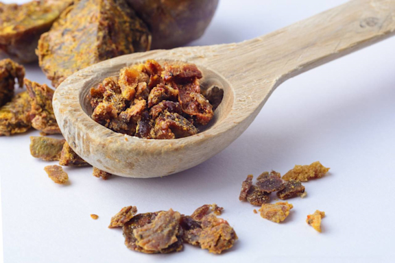 Ein Holzlöffel mit Propolis-Granulat.