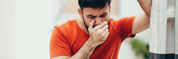 Mann hält sich Hand vor den Mund bei Übelkeit