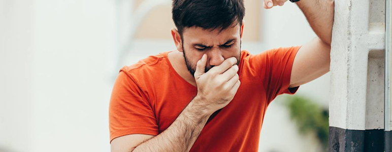 Mann hält sich Hand vor den Mund bei Übelkeit
