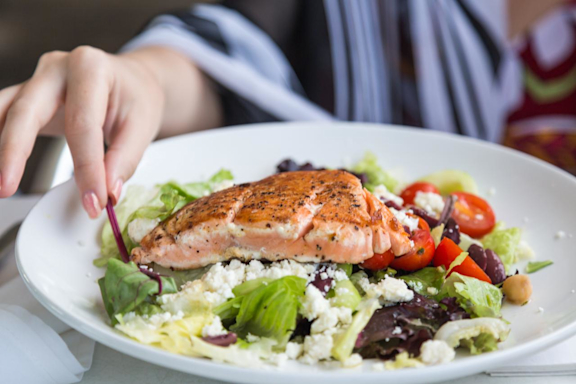 Teller mit leichtem Essen, wie Lachs und Salat.