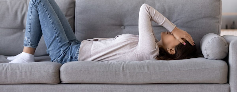 Frau auf Couch mit Händen über dem Kopf