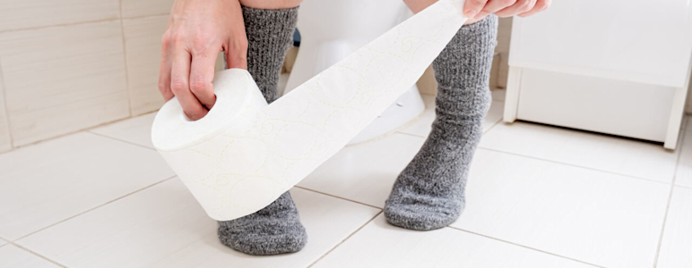 Hände greifen nach Toilettenpapier auf Toilette.