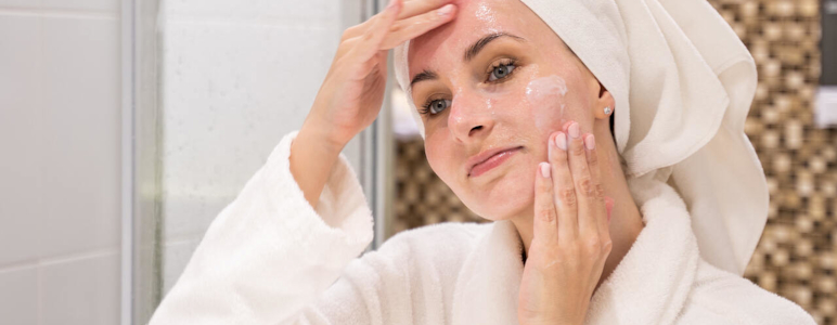 Frau im Badezimmer behandelt ihr Gesicht mit Gel.