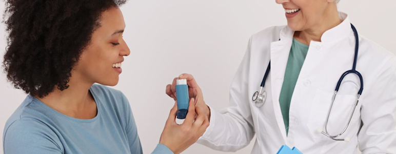 Eine Ärztin reicht einer Patientin mit Asthma einen Inhalator.