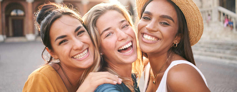 Drei Frauen lachen in die Kamera.