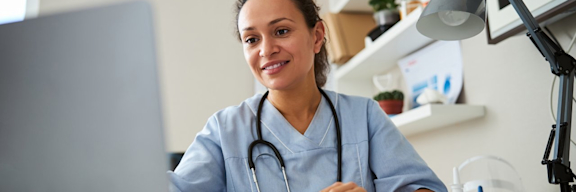 Junge Ärztin in der Online-Sprechstunde vor ihrem Laptop.