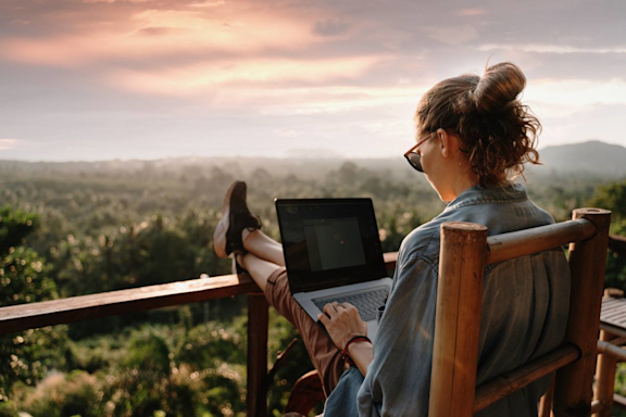 Frau mit Laptop im Urlaub auf der Terrasse oder Balkon.