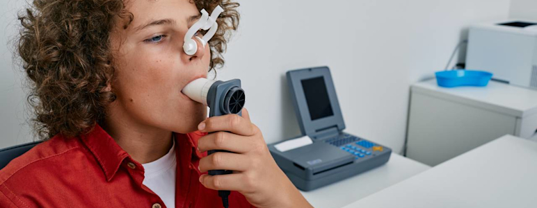 Ein Junge macht in einer Arztpraxis einen Lungenfunktionstest mittels Spirometrie.