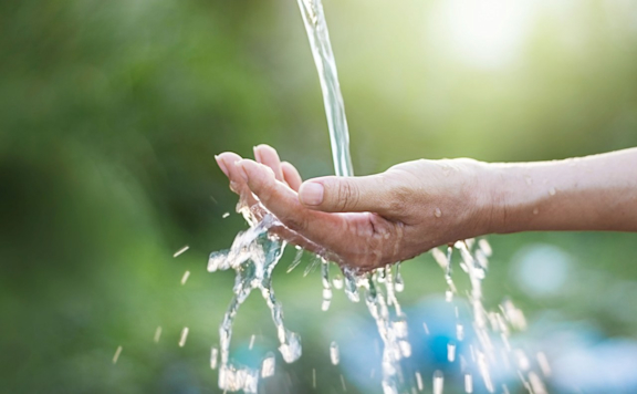 Wasser läuft über die Hand einer Frau im Freien.