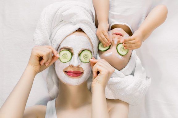 Mutter und Tochter machen gemeinsam Wellness mit einer Gesichtsmaske aus Gurken.
