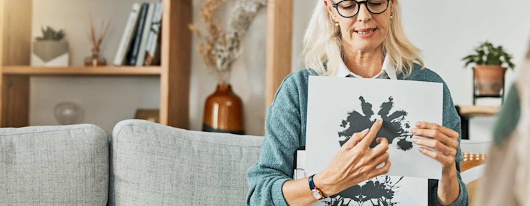 Psychologin sitzt auf Sofa und zeigt einen Rohrschachtest.