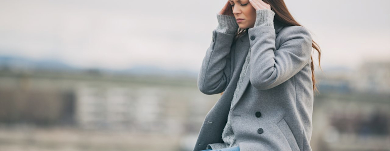 Junge Frau hat Kopfschmerzen durch Wetterumschwung.