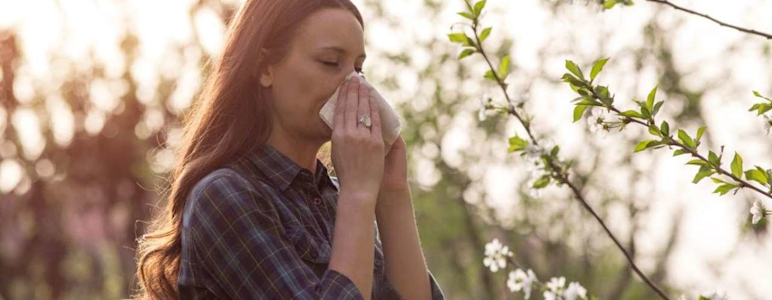 Frau Nase putzend zwischen Baumblüten