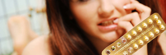 Eine junge Frau schaut verzweifelt auf die halb aufgebrauchte Packung ihrer Antibabypille.