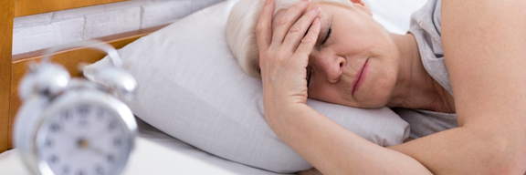 Frau liegt mit Migräne im Bett.