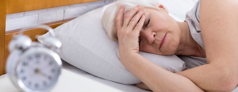 Frau liegt mit Migräne im Bett.
