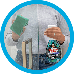 A person cleaning soap scum of shower glass with CleanFreak Unstopables