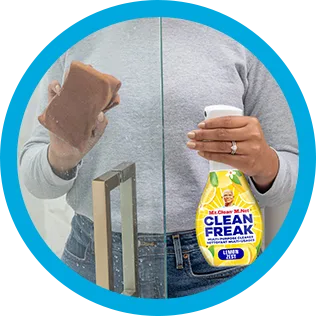 Personne nettoyant des résidus de savon sur une paroi vitrée de douche avec Clean Freak, parfum de citron