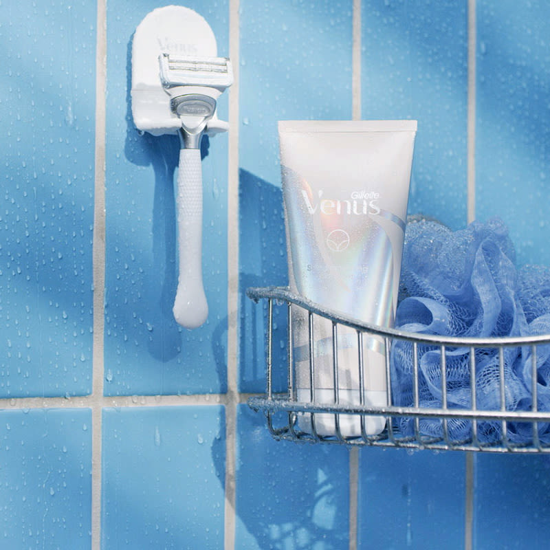 Exfoliant and razor in the bathroom, each placed on its own shelf