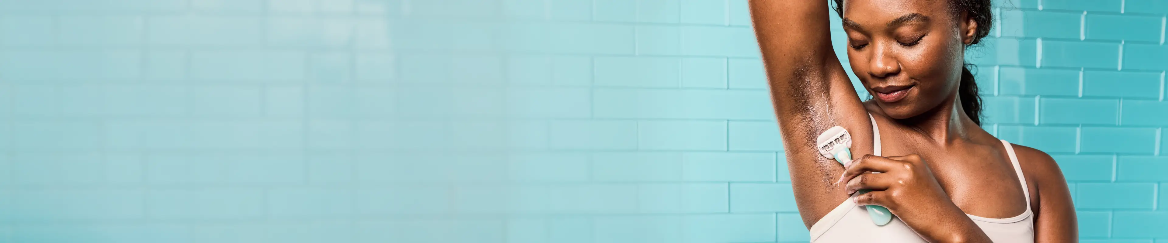 Femme se rasant les aisselles dans une salle de bains, mettant en valeur la technique de rasage et les soins de la peau dans un cadre lumineux.