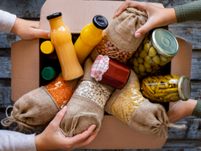 A cardboard box overflowing with juice and pantry items.