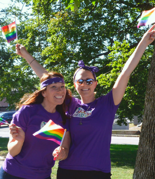 Two commonwealth employees wave pride flags