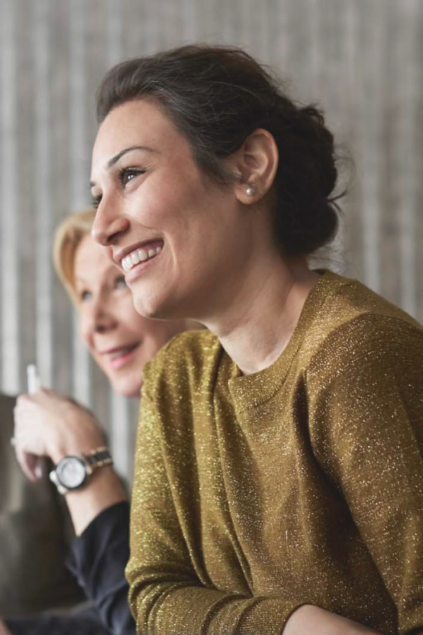 Woman with a gold sweater smiles and looks to the side