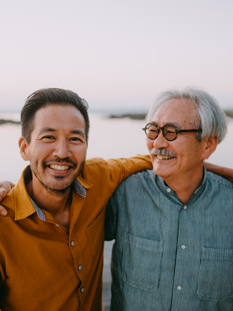 Happy senior father and adult son on beach