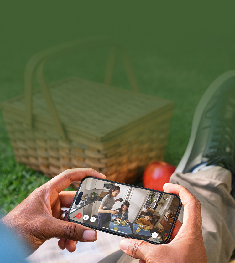 Person looking down at phone featuring video surveillance at a picnic.
