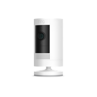 A white Stick Up Cam Battery with black front panel sits on a round base, offering wire-free indoor and outdoor security monitoring.