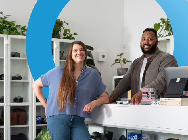 Retail business owner and customer smile from counter of retail store equipped with Ring security devices.