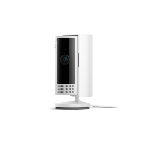 A plug-in white Ring Indoor Cam with black front panel sits on a rounded base.