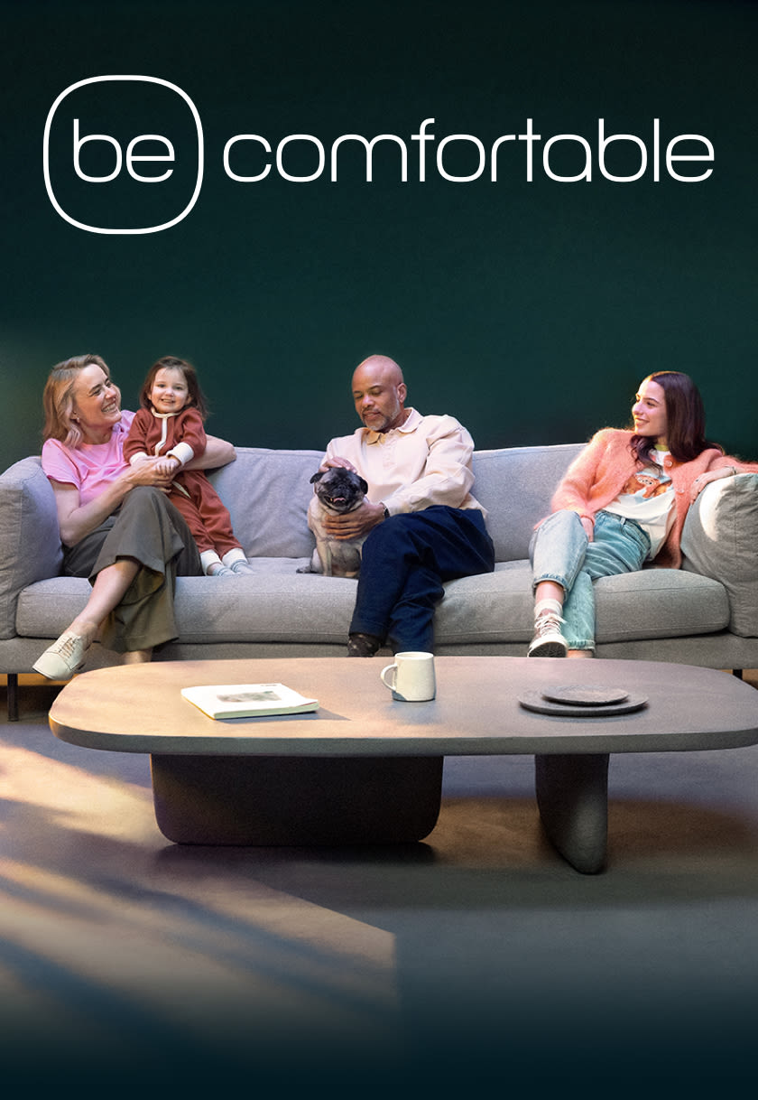 A family sits in a green living room with their dogs.