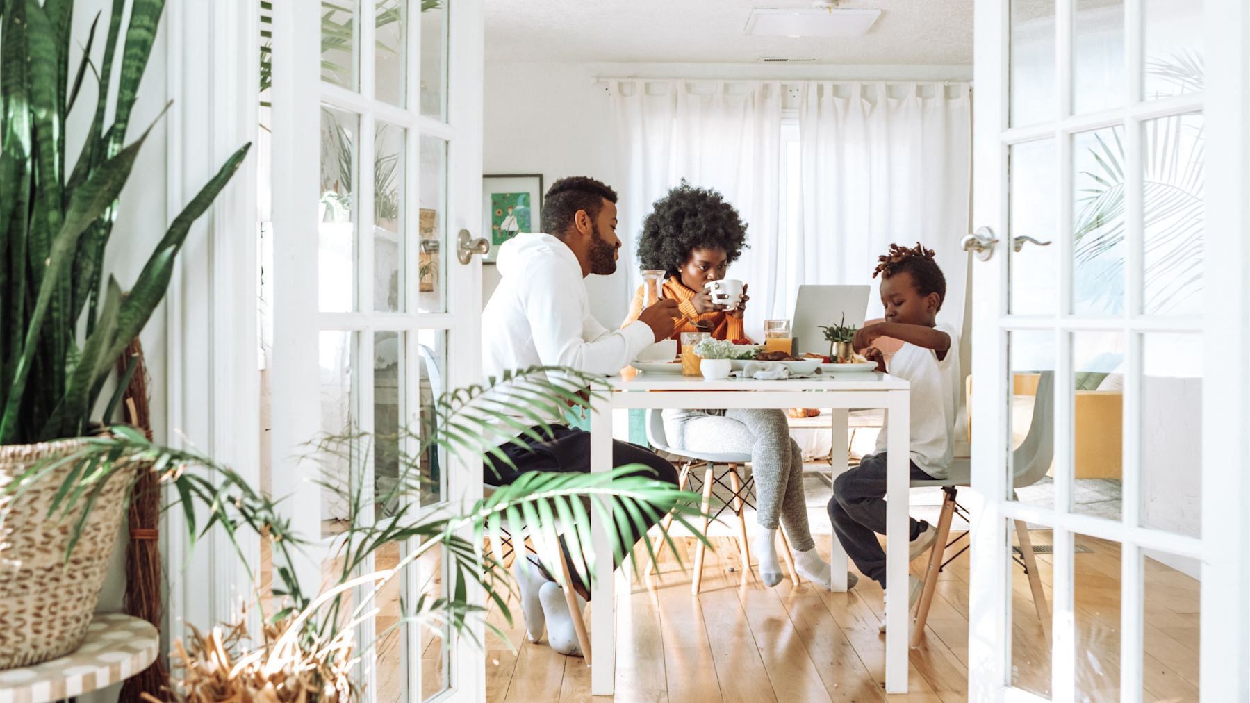 Family of three eating at their kitchen table with the windows open.