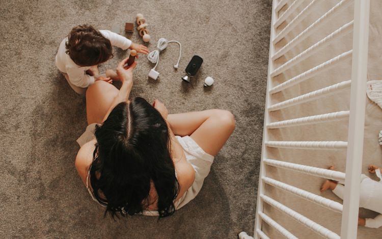 Overhead view of a baby and little girl playing together on the floor.
