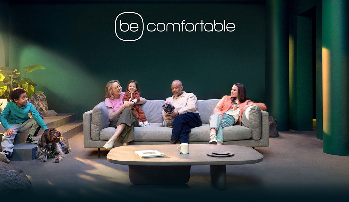 A family sits in a green living room with their dogs.