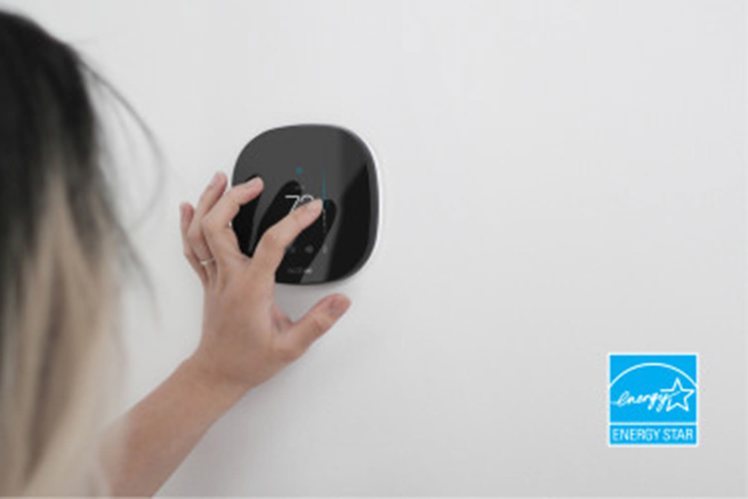 Woman adjusting ecobee thermostat, with ENERGY STAR logo in corner of image.