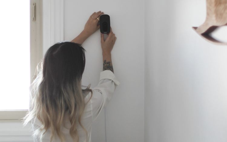 A woman sets up an ecobee SmartCamera on her wall.