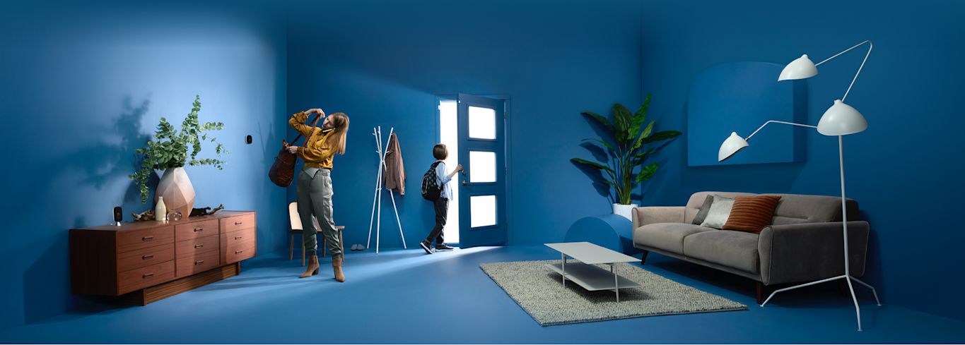 A woman and child get ready to leave a house, with an ecobee thermostat and camera also in frame.