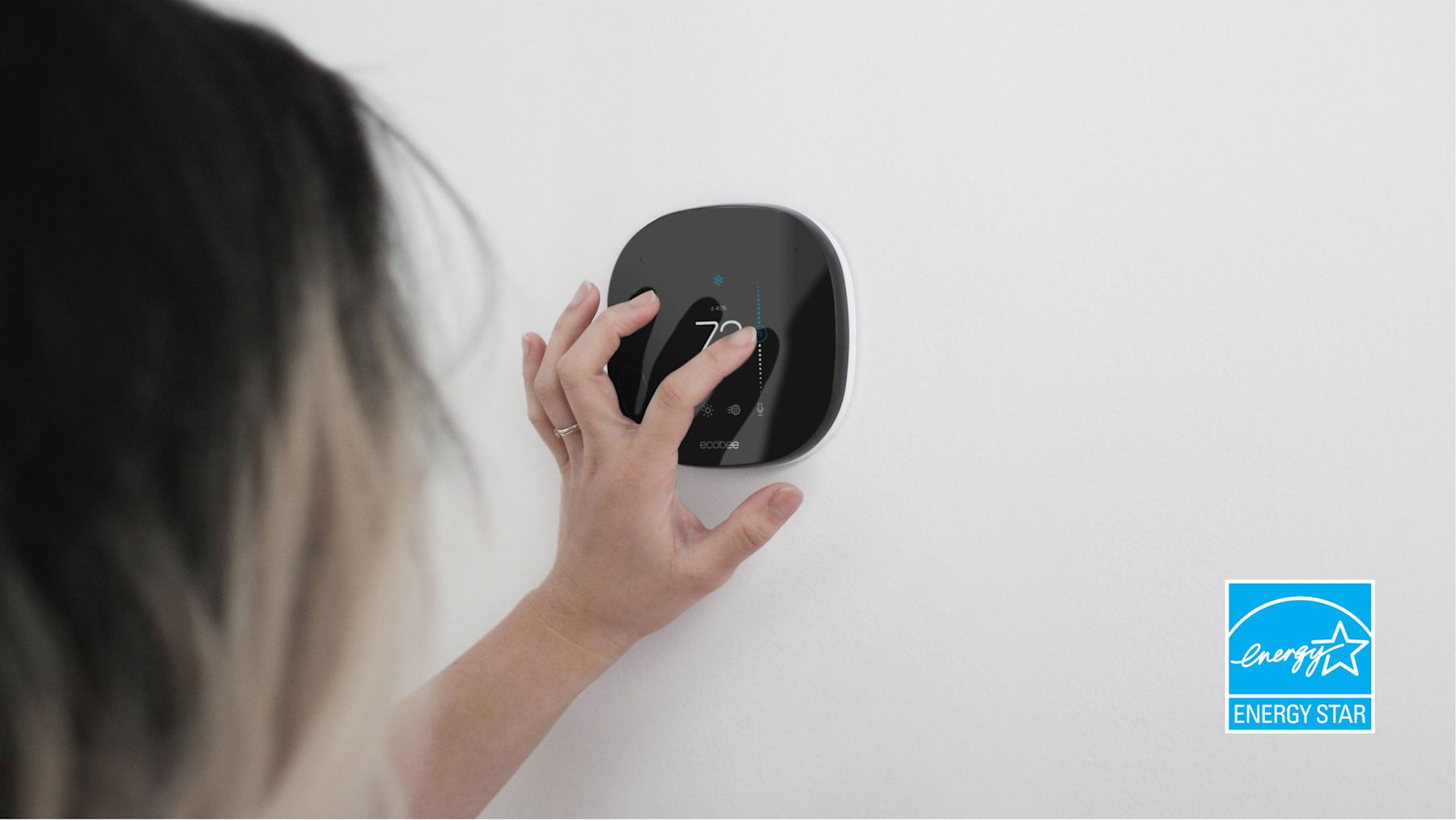 Woman adjusting ecobee thermostat, with ENERGY STAR logo in corner of image.